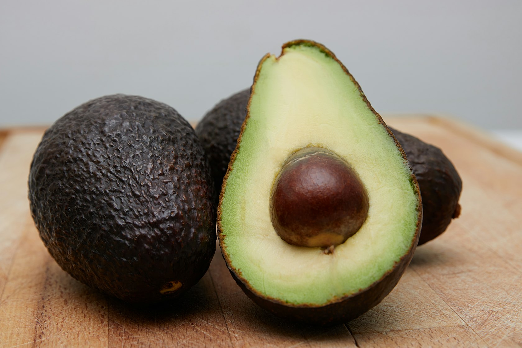Hass avocados cut in half on a wooden board